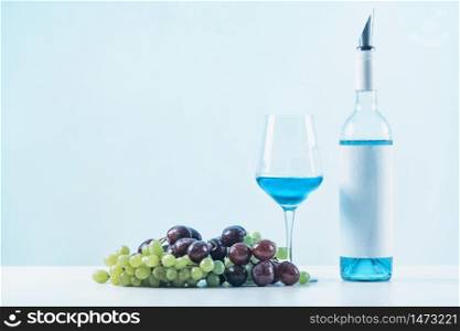 Bottle of blue wine, wine glass and grapes on table.. Blue Wine