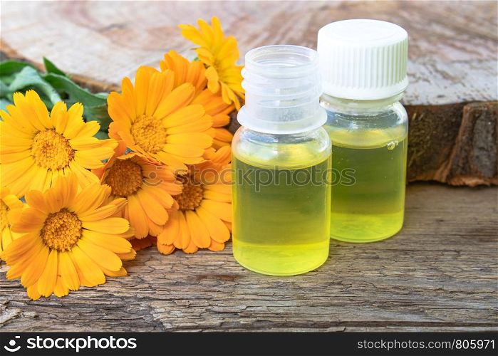 Bottle of calendula oil on a wooden background. Extract of tincture of calendula. Medicinal plants.. Bottle of calendula oil on a wooden background. Extract of tincture of calendula.