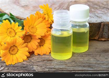 Bottle of calendula oil on a wooden background. Extract of tincture of calendula. Medicinal plants.. Bottle of calendula oil on a wooden background. Extract of tincture of calendula.