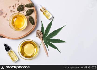 Bottle of CBD oil, THC tincture, cannabis leave, hemp seed on the wooden bowl arranged together on the white background. Hemp plant cannabidiol distillation into liquid for medical use.. Distillation concept of CBD oil feature with hemp seeds on the white background.