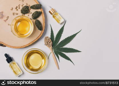 Bottle of CBD oil, THC tincture, cannabis leave, hemp seed on the wooden bowl arranged together on the white background. Hemp plant cannabidiol distillation into liquid for medical use.. Distillation concept of CBD oil feature with hemp seeds on the white background.