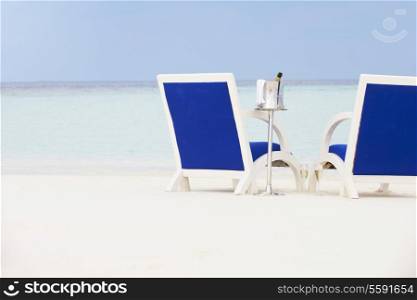 Bottle Of Champagne Between Chairs On Beautiful Beach