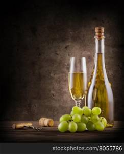 Bottle of champagne with grapes and glass on wooden table. Bottle of champagne with grapes and glass