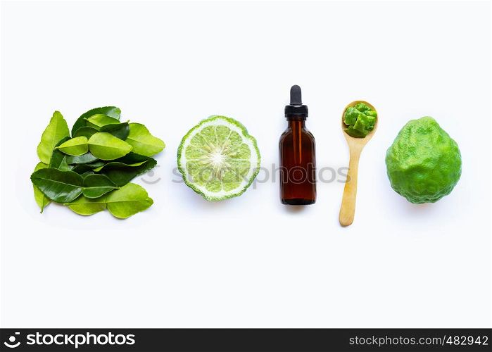 Bottle of essential oil and fresh kaffir lime or bergamot fruit with leaves isolated on white background.