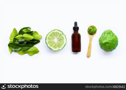 Bottle of essential oil and fresh kaffir lime or bergamot fruit with leaves isolated on white background.