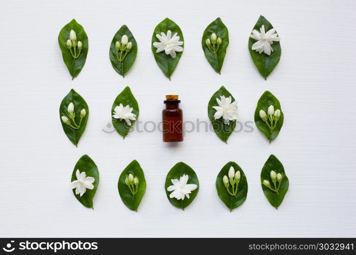 Bottle of essential oil with jasmine flower and leaves.. Bottle of essential oil with jasmine flower and leaves on white background.