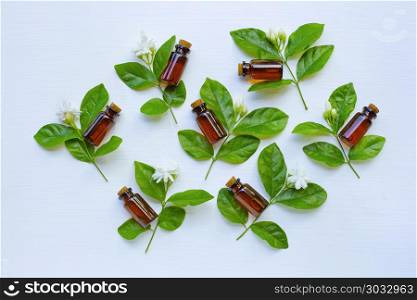 Bottle of essential oil with jasmine flower and leaves.. Bottle of essential oil with jasmine flower and leaves on white background.