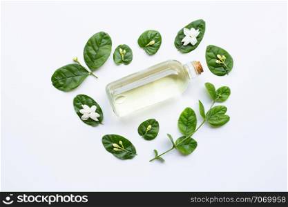 Bottle of essential oil with jasmine flower and leaves on white background.