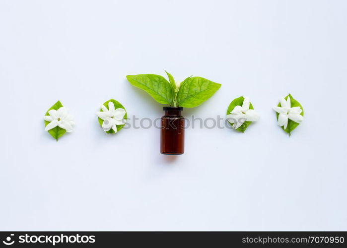 Bottle of essential oil with jasmine flower and leaves on white background.