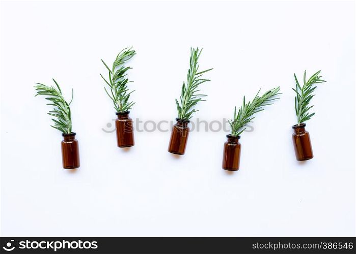 Bottle of essential oil with rosemary on white background.