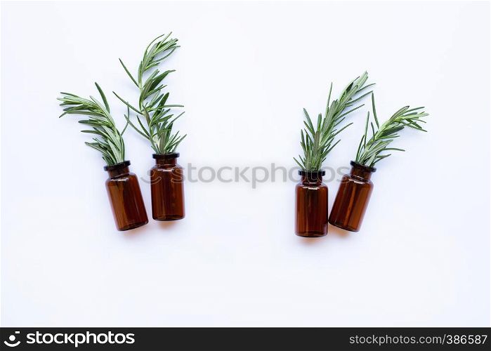 Bottle of essential oil with rosemary on white background. Copy space