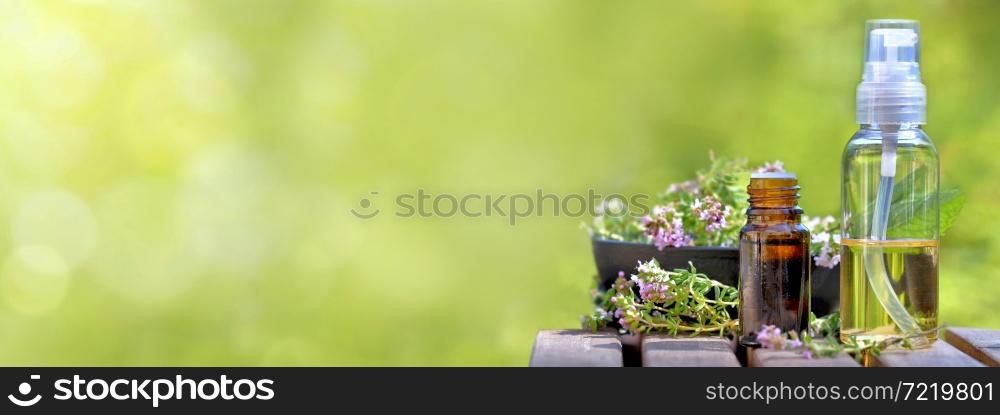 bottle of essential oils spilled on a table with lavender flowers on green bokeh background