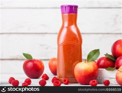 Bottle of fresh organic apple and raspberry juice with fresh fruits in box on wooden background. Space for text