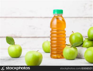 Bottle of fresh organic apple juice with healthy green apples in box on wooden background. Space for text