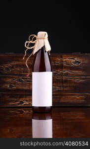 Bottle of home brewed craft beer with blank label template on a reflective surface with a wooden chest in the background
