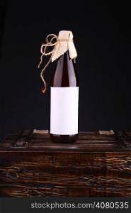 Bottle of home brewed craft beer with blank label template standing on a wooden chest