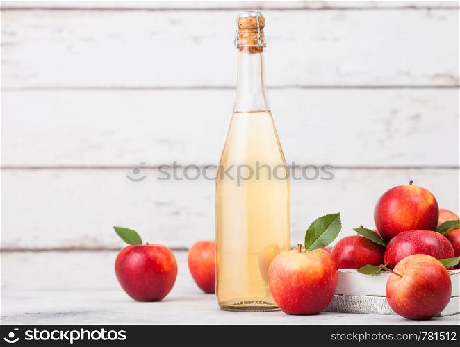Bottle of homemade organic apple cider with fresh apples in box on wooden background, Glass with ice cubes
