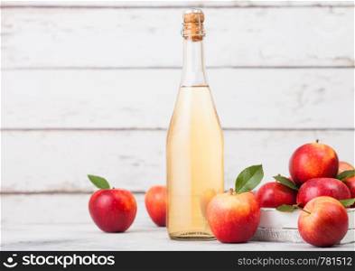Bottle of homemade organic apple cider with fresh apples in box on wooden background, Glass with ice cubes