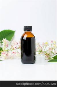 Bottle of horse chestnut extract, essence of chestnut flowers. Flowering branches and leaves of horse chestnut. Production of medicines, tablets, tinctures.. Bottle of horse chestnut extract, essence of chestnut flowers. Flowering branches and leaves of horse chestnut.