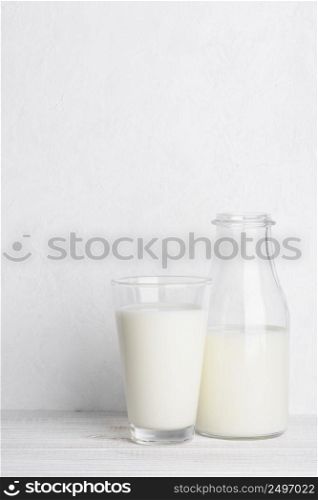 Bottle of milk ang glass of milk on white wooden table background vertical with copy space