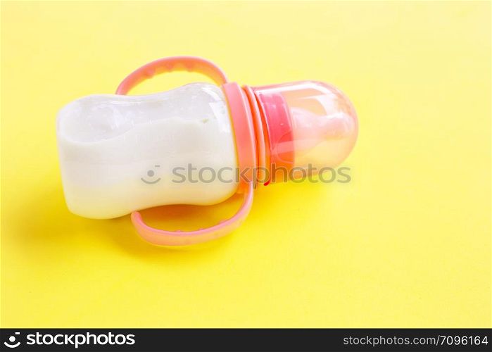 Bottle of milk for baby on yellow background.