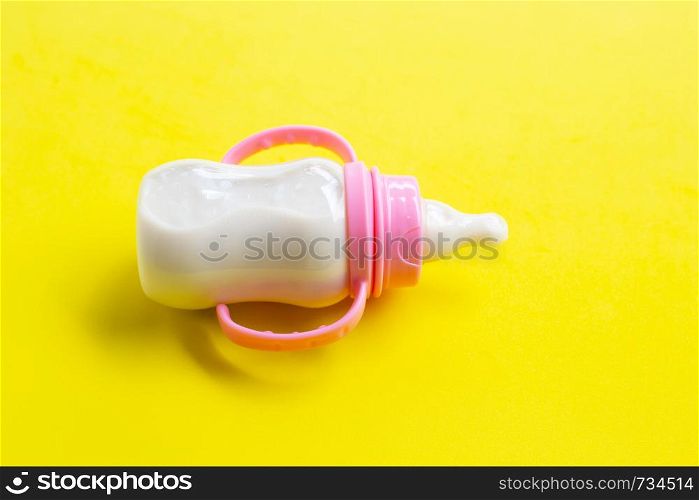Bottle of milk for baby on yellow background.