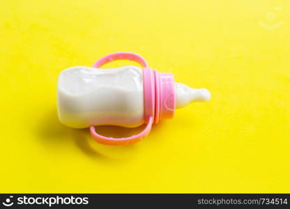 Bottle of milk for baby on yellow background.