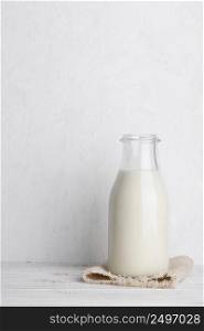 Bottle of milk on a sack cloth on white wooden table background vertical with copy space