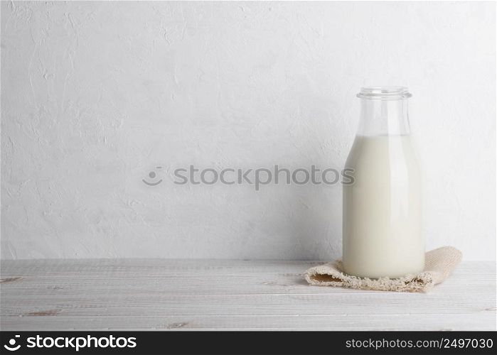 Bottle of milk on a sack cloth on white wooden table background horizontal with copy space