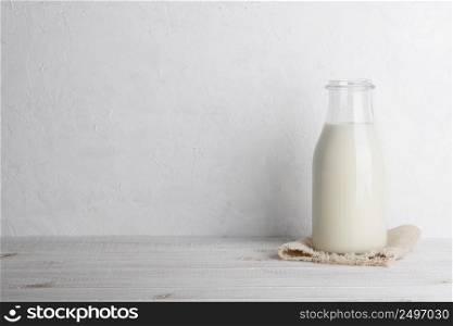 Bottle of milk on a sack cloth on white wooden table background horizontal with copy space