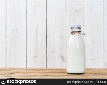 Bottle of milk on a wooden vintage table, white wooden background with copy space. Fresh milk, reusable glassware