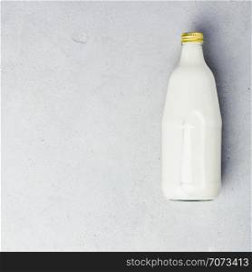 Bottle of milk on grey concrete background, flat lay