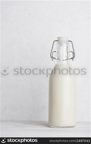 Bottle of milk with swing top closed on white wooden table background