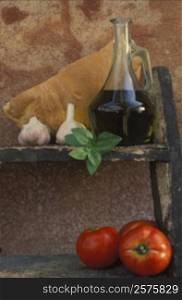 Bottle of olive oil and two tomatoes on a shelf
