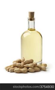 Bottle of peanut oil and peanuts on white background
