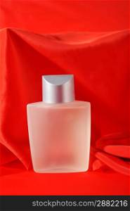 Bottle of perfume, isolated on red close up