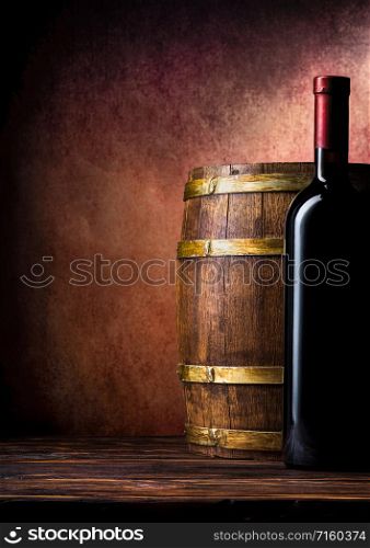 Bottle of red wine and barrel on burgundy background. Bottle and barrel on burgundy