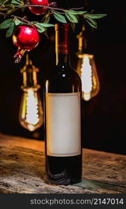Bottle of red wine and branch of garnet on a background of vintage lamps. Wine and garnet