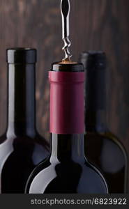 Bottle of red wine and corkscrew. Bottle of red wine and corkscrew on an old wooden table