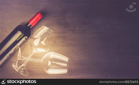 Bottle of red wine and two wine glasses on dark table with copy space, toned image. Glass of red wine