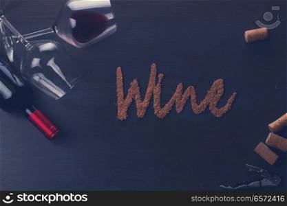 Bottle of red wine and two wine glasses on table with wine word letters, retro toned. Glass of red wine