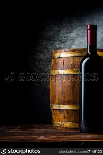 Bottle of red wine and wooden barrel on a black background. Bottle and barrel on black