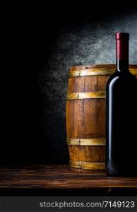 Bottle of red wine and wooden barrel on a black background. Bottle and barrel on black