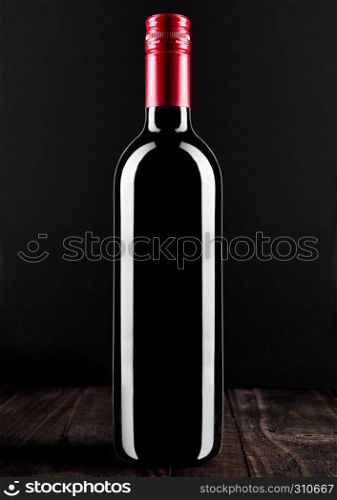 Bottle of red wine dark glass on wooden bacground red top