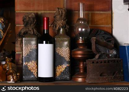 Bottle of red wine with a blank label template standing on a fireplace shelf with various vintage objects