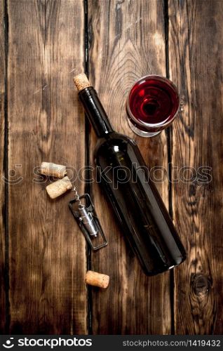 Bottle of red wine with a corkscrew and corks. On a wooden table.. Bottle of red wine with a corkscrew and corks.