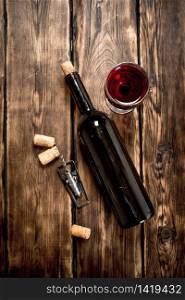 Bottle of red wine with a corkscrew and corks. On a wooden table.. Bottle of red wine with a corkscrew and corks.