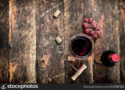 bottle of red wine with a corkscrew. On a wooden background.. bottle of red wine with a corkscrew.