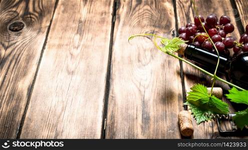 Bottle of red wine with a sprig of grapes. On a wooden table.. Bottle red wine with a sprig of grapes.