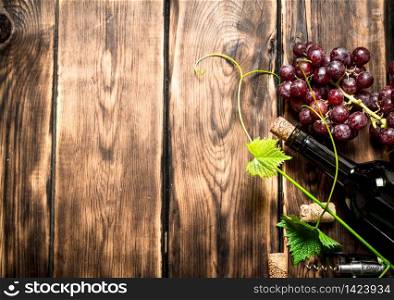 Bottle of red wine with a sprig of grapes. On a wooden table.. Bottle red wine with a sprig of grapes.
